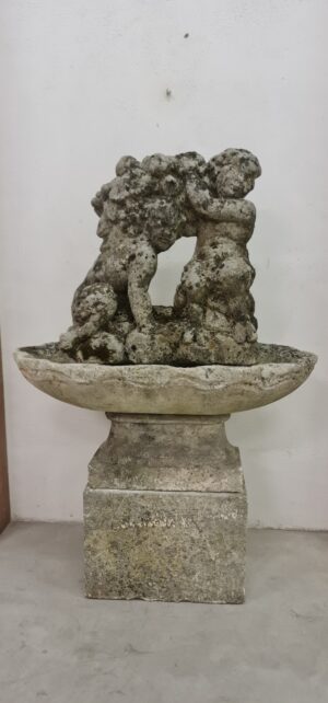 Putti con frutta in pietra su una conchiglia sorretta da un basamento